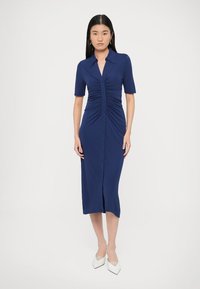 Φόρεμα σε σκούρο μπλε ναυτικό χρώμα, με κουμπιά, κατασκευασμένο από ελαστικό ύφασμα, διαθέτει κοντά μανίκια, ρετσίνα λεπτομέρειες και μήκος μέχρι τη μέση της γάμπας.