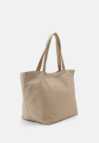 Beige canvas axelväska med två axelremmar. Mjuk textur och öppen toppdesign, strukturerad form utan synliga detaljer eller accenter.