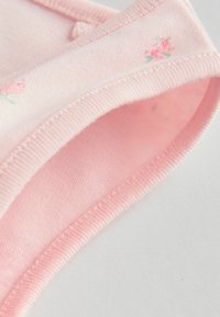 Roosa puuvillane kangas väikeste lillemustritega, millel on sooneline kaelus ja sile tekstuur. Õmblused on peened ja korrektsed.