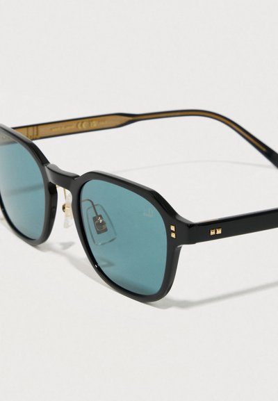 Mustad prillid ruudukujuliste läätsedega, teise värviga ja kuldsete aktsentidega, tekstuuriga käepidemed. Sisaldab tumedaid raame ja väikeseid dekoratiivseid nuppe.