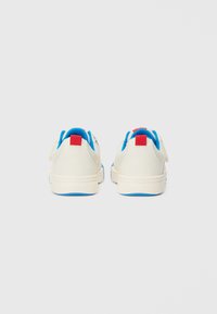 Sneakers with a cream upper, blue interior, and red heel tab. Features a rounded shape and textured fabric for durability and comfort.