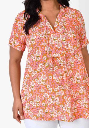 Florale Tunika in Orange mit weißen und rosa Blumen. Kurze Ärmel, V-Ausschnitt, lockere Passform und leichtes Material. Nahtdetails an der Vorderseite.