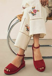 Rode suède platform sandalen met een verstelbare enkelband, met een gladde textuur en contrasterende geweven details langs de zool.