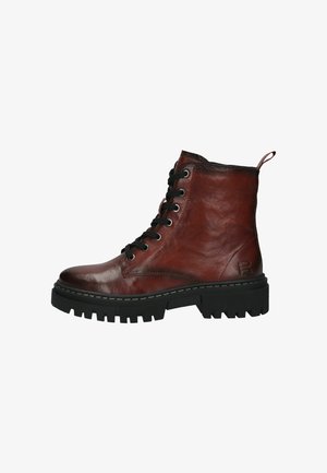 Botas de tobillo de cuero marrón con cordones, con un acabado texturizado, que cuentan con una suela gruesa y resistente de color negro y cordones negros, además de un tirador en el talón.