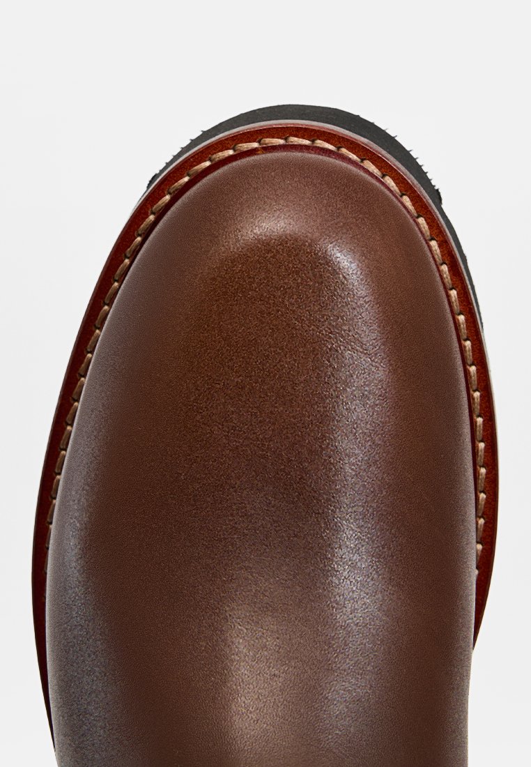 Brauner Lederstiefel mit runder Spitze, glatter Textur und kontrastierenden Nähten entlang der Sohle. Schwarze Gummisohle und saubere Kanten.