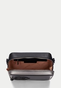 Borsa a tracolla in pelle nera con texture e un accento argento. Il compartimento principale presenta un interno beige con uno slot per le carte e una chiusura a zip.