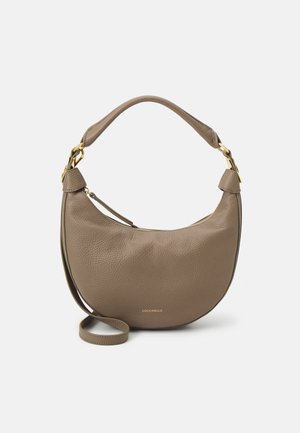 Taupe crescent-shaped leather handbag with short handle, long strap, gold hardware, and small embossed brand name at the bottom center.