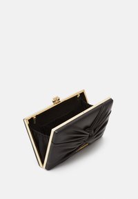 Clutch in pelle nera con un design annodato sul fronte, hardware dorato e una struttura rigida. L'interno presenta una fodera in tessuto.