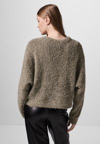 Överdimensionerad, stickad tröja i texturerad olivgrön med en lös passform. Har en bred rund halsringning och sänkta axlar.