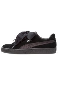 Baskets Puma en daim noir avec de larges lacets en satin noués en nœud et une bande Puma foncée sur le côté, présentées de profil sur un fond blanc.