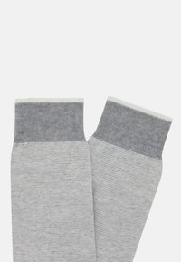 Calze in cotone grigio misto con un risvolto a costine grigio scuro e una consistenza morbida, caratterizzate da un motivo a righe lungo il corpo.