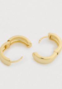 Cercei hoop din aur cu un design curbat și robust. Finisaj metalic neted cu textură lustruită și închidere sigură cu clemă.