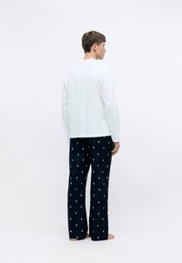 Un haut à manches longues blanc associé à un pantalon bleu marine orné d'un motif de petits points multicolores. Matière en coton doux, coupe décontractée.