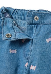 Pantalones cortos de mezclilla con cintura elástica, con cierre de botón plateado y patrones de huesos multicolores. Tejido azul claro, acabado texturizado.