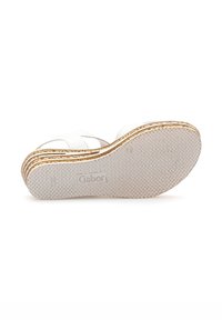 White sandal with a textured rubber sole, layered design, and subtle gold accent along the edge. Logo embossed on the bottom.