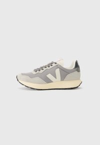Gray athletic shoe with mesh and suede materials, featuring a cream sole, gray laces, and a prominent 'V' logo on the side.