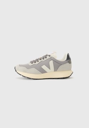 Gray athletic shoe with mesh and suede materials, featuring a cream sole, gray laces, and a prominent 'V' logo on the side.