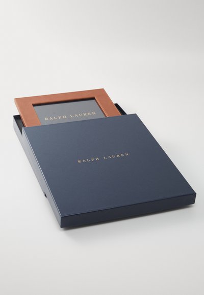 Ralph Lauren fotokadra ar brūnu ādas apdari, pasniegta tumši zila kastē ar zeltīti iepresētā logo uz vāka.