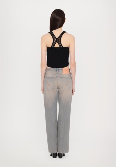 Black cropped tank top with a textured design and crossed straps, paired with light grey wide-leg jeans featuring back pockets and a brand label.