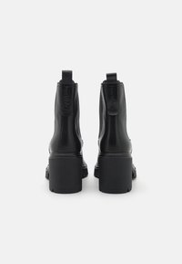 Stivali neri in pelle alla caviglia con tacco alto, pannelli elastici laterali e linguette sul retro. Finitura liscia senza motivi visibili.