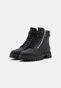 Bottines noires à lacets avec un matériau texturé, fermeture éclair sur le côté et semelle épaisse. Présente un motif embossé complexe et des accents métalliques robustes.
