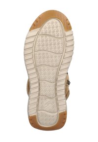 Suela de zapatilla de goma con un patrón texturizado que presenta estrías y surcos. Color: beige claro con acentos tonos marrones. Forma redondeada.