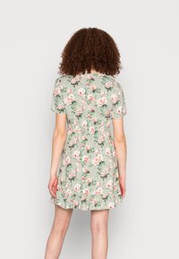 Vestido floral em verde claro, mangas curtas, cintura elástica, com bainha franzida, apresenta rosas cor-de-rosa e brancas com folhas verdes por toda a peça.