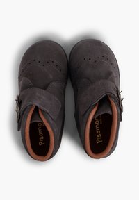Zapatos infantiles de ante gris oscuro con cierre de tira, perforaciones decorativas y forro interior marrón. Punta redondeada y suela resistente.