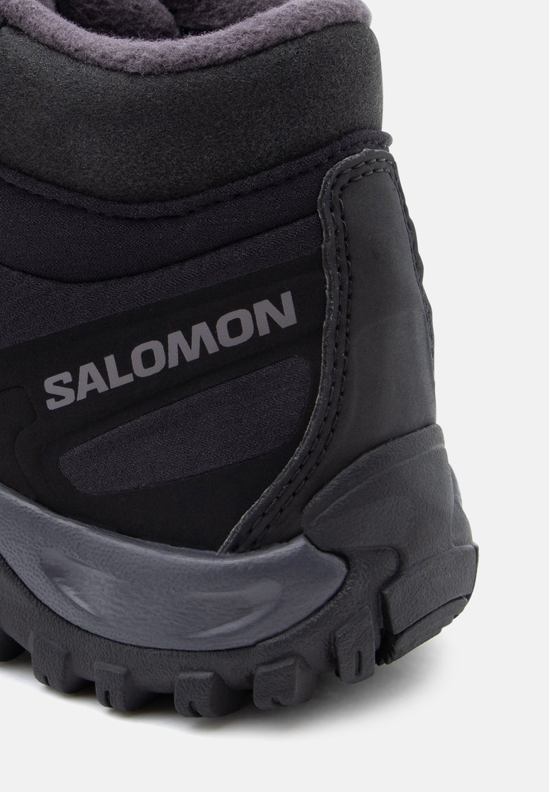 Schwarzer Wanderschuh mit gepolstertem Schaft, strukturiertem Obermaterial, Gummisohle und grauen Akzenten. Mit dem "Salomon"-Logo an der Seite.