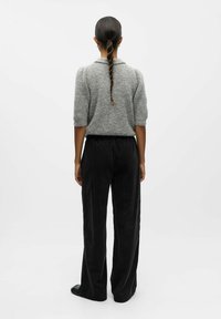 Maglione grigio peloso con maniche corte, abbinato a pantaloni a gamba larga in corduroy neri. Design semplice, texture evidente e cintura elastica.