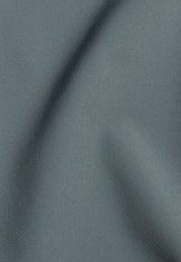 Tessuto grigio medio, liscio, con sottili pieghe diagonali e una texture morbida sotto una luce uniforme.