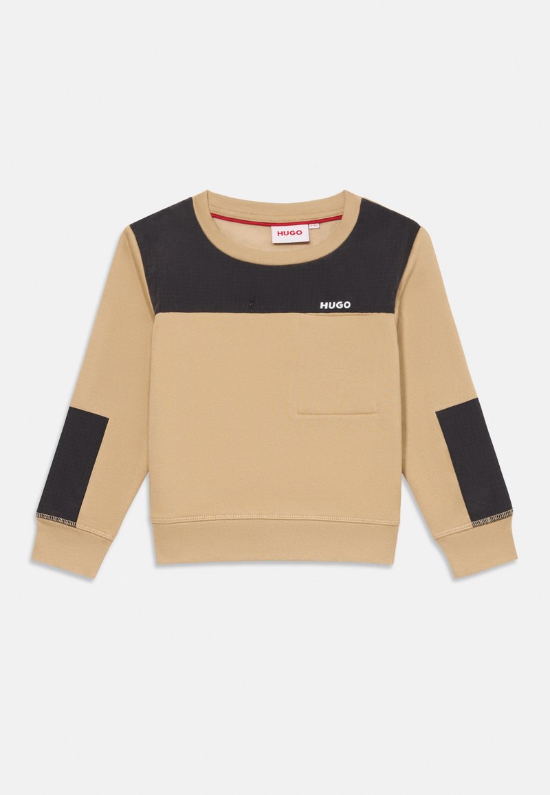 Camisa de manga longa bege com remendos pretos no peito e nos cotovelos, pequeno bolso no peito e logotipo "HUGO" no peito e na etiqueta do colarinho.