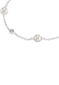 Collana in argento con due perle bianche e una pietra decorativa trasparente tra di esse. Design semplice ed elegante con una leggera lucentezza.
