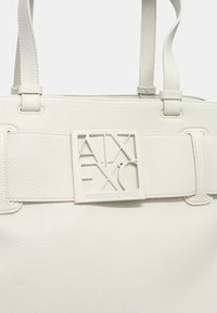 Borsa a tracolla bianca in pelle con superficie testurizzata, dotata di una prominente placca logo rettangolare e doppi manici.