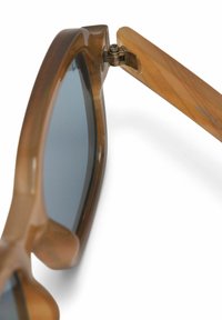 Brown transparent sunglasses with blue lenses, featuring a prominent frame, smooth texture, and metallic hinge detail on the temples.