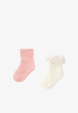 Deux chaussettes de bébé côte à côte, l'une rose avec un bord en dentelle, l'autre blanche avec un galon en dentelle à volants et un petit nœud.