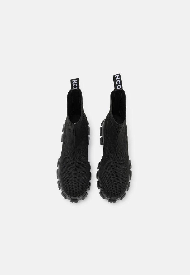 Bottines noires avec une tige en tissu texturé et une semelle en caoutchouc épaisse. Équipées de tirettes avec la marque "NCO". Design élégant et moderne.