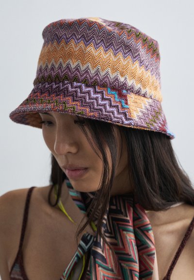 Έγχρωμο πλεκτό καπέλο τύπου κουβά με ζιγκ-ζαγκ σχέδιο σε μοβ, πορτοκαλί και πράσινο. Διαθέτει μαλακή υφή και φαρδύ, ευέλικτο γείσο.