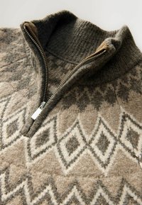 Brauner Wolle-Zip-Pullover mit hohem Kragen, Rautenmuster in Beige- und Grautönen sowie einem Metallreißverschluss. Sichtbare strukturelle Strickdetails.