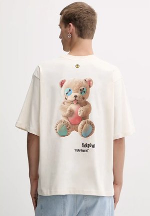 T-shirt oversize color crema con una grafica di un orso di peluche con bottoni blu e dettagli rosa, insieme al testo "BARROW 'PERFORMERS'".