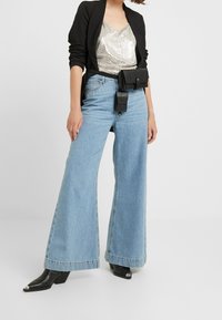 Vidbenade ljusblå jeans, silverpailleterad topp, svart blazer och en svart bälvväskan. Svarta klackstövlar med metalliska detaljer.