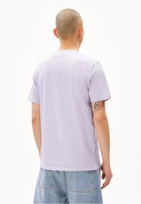 Helles lila Baumwoll-T-Shirt mit kurzen Ärmeln, rundem Halsausschnitt und leicht lockerer Passform. Die Rückansicht zeigt ein schlichtes Design ohne Grafiken.