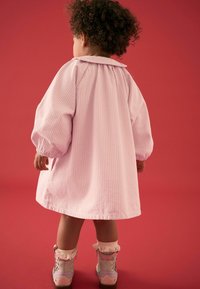 Rosa randig klänning med puffärmar och krage, tillsammans med ljusgrå stövlar med rosa accenter och spetsdetaljer.