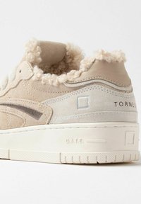 Sneaker beige con tomaia in camoscio, fodera morbida alla caviglia e suola in gomma bianca. Presenta cuciture sottili e dettagli del marchio.