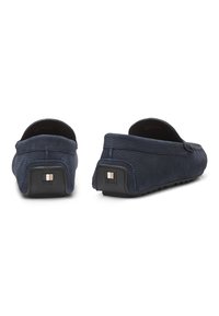 Pantalones de cuero azul marino con un acabado texturizado, que presentan un perfil bajo y una suela de goma. Acentuados con un logo cuadrado en el talón.