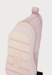 Ροζ σουέτ παπούτσι με καουτσούκ σόλα, διαθέτει υφή στο σχέδιο, ταμπελάκι στη φτέρνα και ορατό λογότυπο της μάρκας στη σόλα.