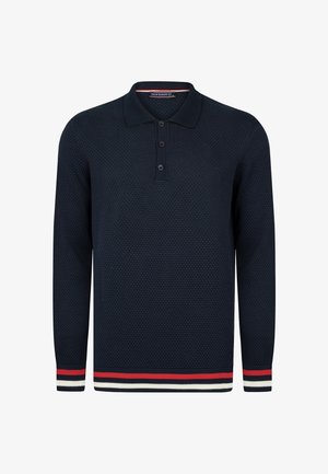 Tumedat sinised pika varrukaga polo-särk, millel on tekstuurne kudumismuster, kolm musta nuppu ja triibuline äär punastes, valgetes ja tumedates sinistes toonides.