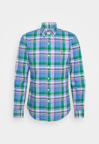 Košile s dlouhými rukávy, zapínaná na knoflíky, s kostkovaným vzorem v modré, zelené, bílé a růžové barvě a malým vyšitým logem na levé straně hrudníku.