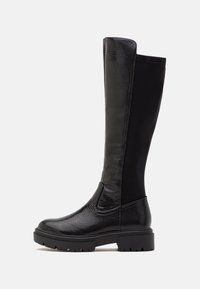 Bottes noires arrivant au genou avec un devant en cuir texturé et un dos en tissu extensible, dotées d'une semelle en caoutchouc épaisse et d'un design à bout arrondi.