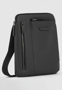 Zwarte leren schoudertas met een gestructureerd oppervlak, voorzien van voorklepzakken met ritssluiting en een afneembare riem voor verstelbare draagopties.